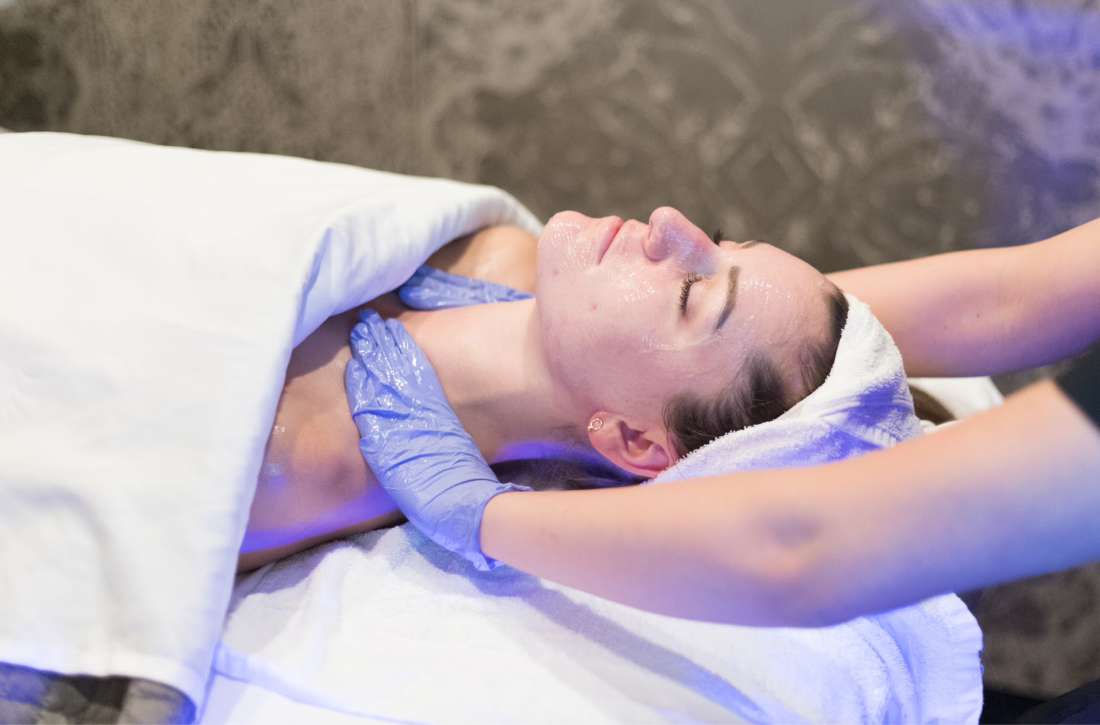 Person receiving a facial treatment with blue light therapy in a spa setting.